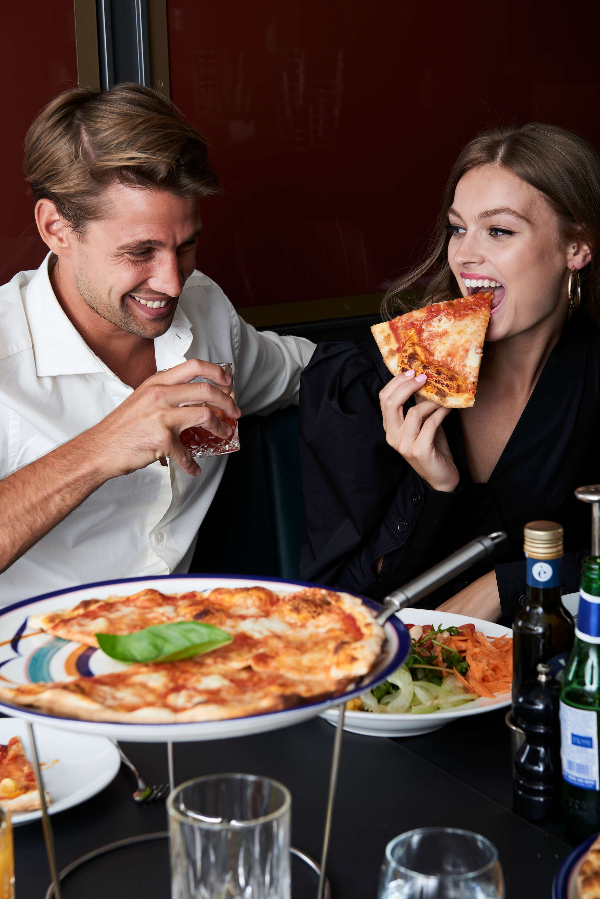 Couple eating pizza and drinking cocktails.