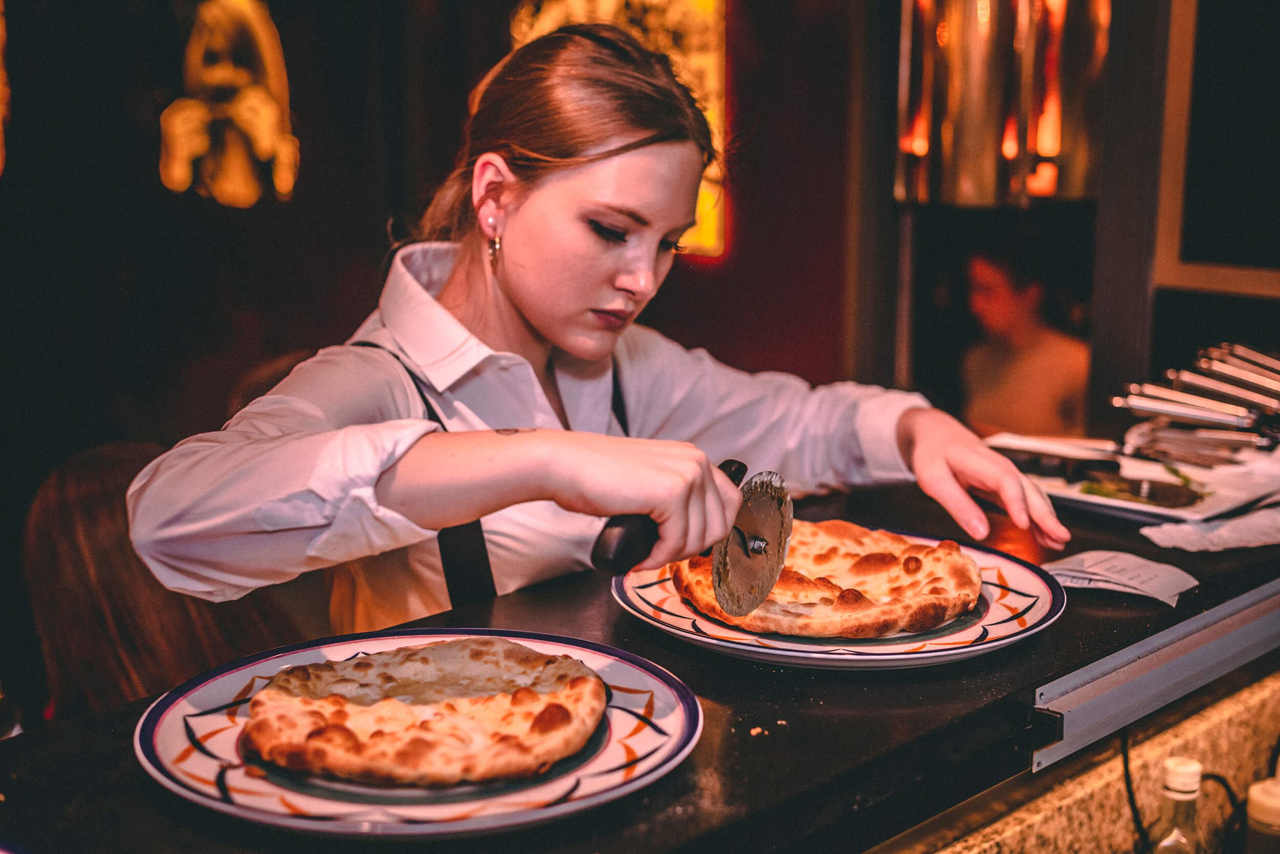 Waitress cutting pizza ready to be served.